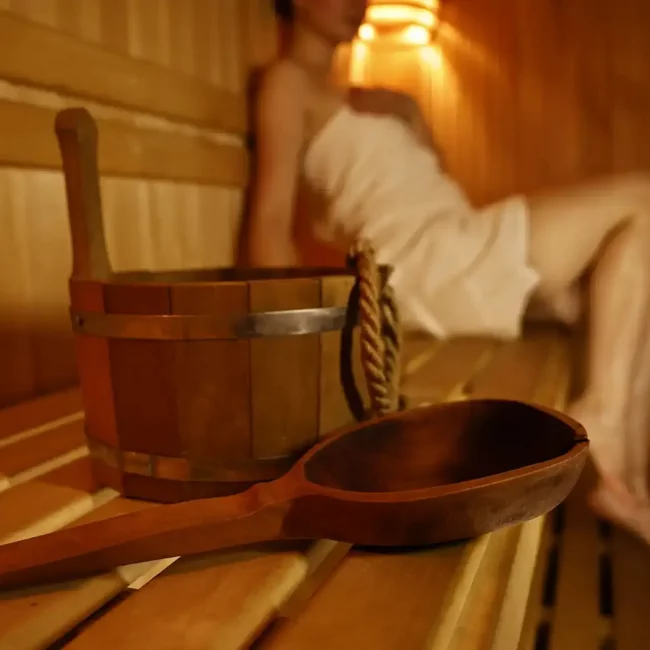 woman-relaxing-in-sauna-with-wooden-bucket